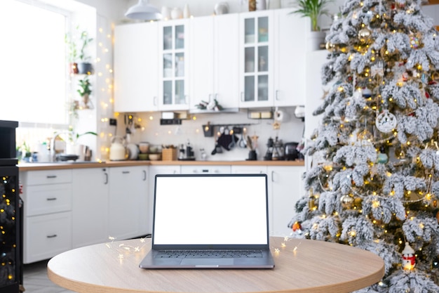 ホワイトスクリーンモックアップのラップトップフェアリーライトで暖かい白い装飾のクリスマスキッチン