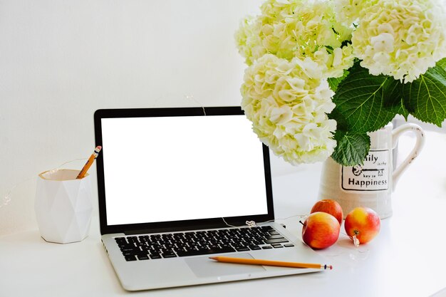 Photo a laptop with a white screen mockup with flowers near working place