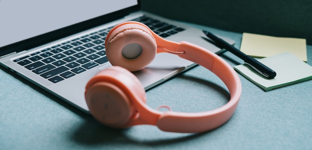 laptop with white screen and pink headphones beside