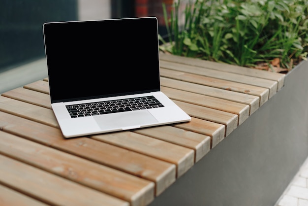 Laptop on a wooden bench outdoors