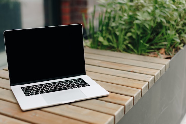 Laptop on a wooden bench outdoors