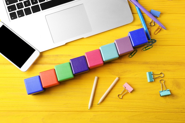 Laptop and wooden cubes on color background