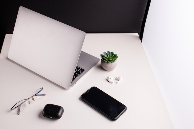 Laptop for work and financial reports phone headphones glasses on a white table