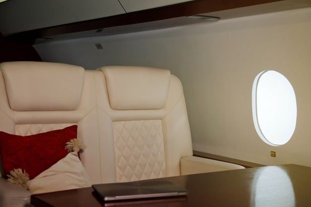 개인 제트기의 고급 인테리어 작업 테이블에 노트북. 장식이있는 현대적이고 편안한 비즈니스 비행기. 항공 산업의 승객 서비스 품질 개념, 최고