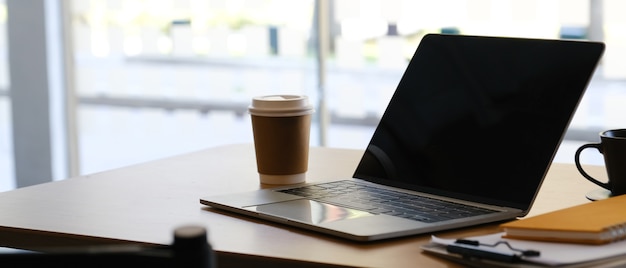 Laptop on workspace with paper cup coffee