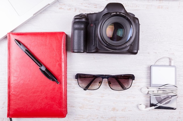 Laptop, writing notebook, camera and musical player on wooden background