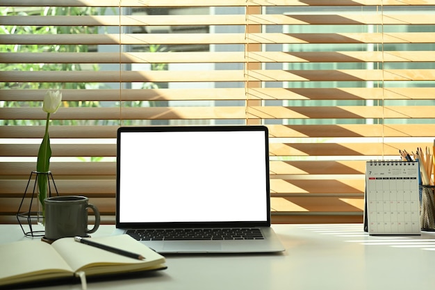 Laptopcomputer kopje koffie kalender en notebook op witte tafel Thuisbureau