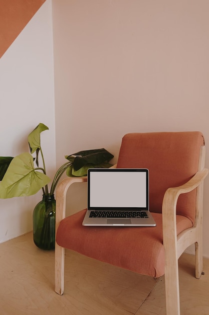 Laptopcomputer met blanco kopie ruimtescherm Minimalistische thuiskantoor bureau werkruimte met comfortabele rode stoel en huisplant Werk thuis