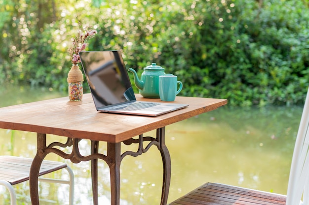 Laptopcomputer met theemok op houten tafel