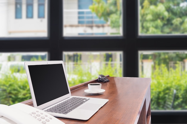 Laptops with white coffee mug on wooden desk