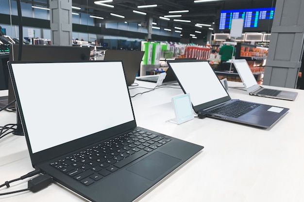 Photo laptops with a white screen at the showcase in the electronics store.