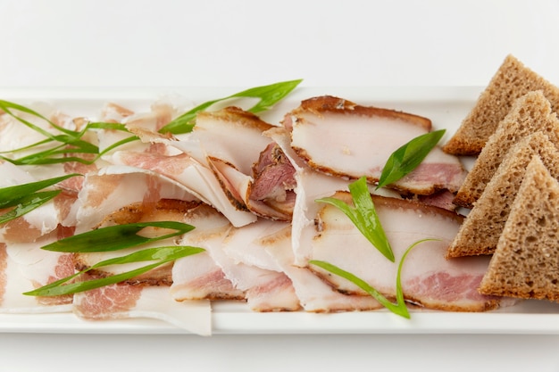 Lard cut into pieces on a grater. Served with herbs and slices of bread. Traditional mouth-watering snack. Close-up. Top view.