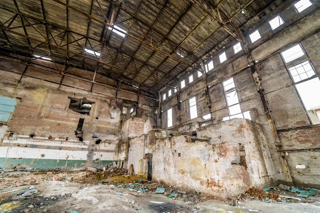 Large abandoned industrial hall. Territory of abandoned industrial area waiting for demolition. An abandoned hangar in misery and without people