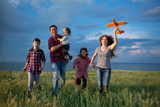 A large active family of five walks at sunset across the field against the blue sky The relationship of parents and children for a walk