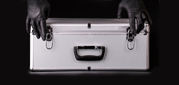 The large aluminum suitcase and hands black safety gloves