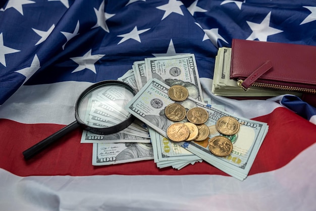 Large amount of American dollars spread out with magnifying glass and wallet on the USA flag