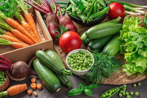 A large assortment of fresh vegetables and herbs on a brown background. Side view.