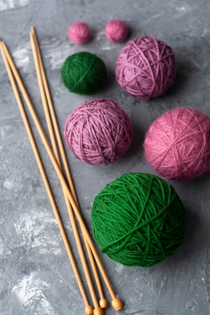 Large balls of green and purple colors and wooden needles on a gray textured concrete background. Place for text.