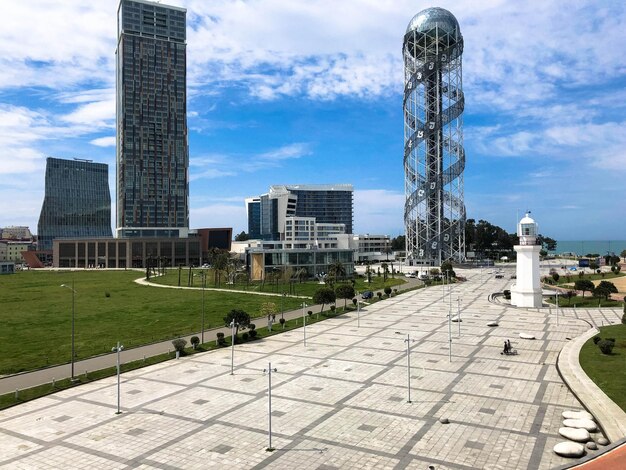 A large beautiful metal modern spiral high architecture tower alphabet a symbol of the city and glass booms buildings skyscrapers on the coast Batumi Georgia April 17 2019