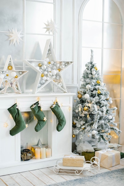 A large beautifully decorated Christmas tree stands in the room next to the fireplace.