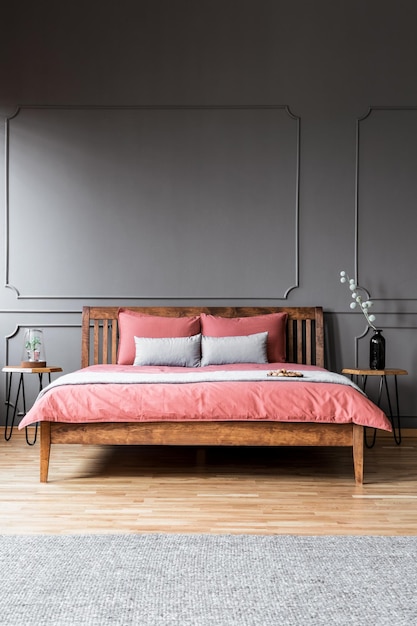 A large bed standing in a dark bedroom interior between bedside