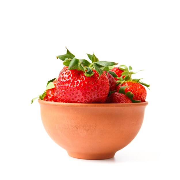 Large berries of organic strawberries in a clay ceramic bowl isolated on a white background