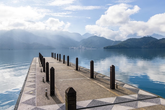 Photo large blue lake surrounded by mountains with pier in the morning at sun moon lake of taiwan