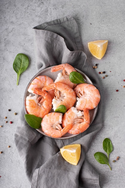 Large boiled shrimp with lemon on a gray plate, top view