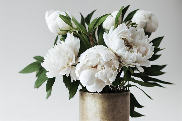 Large bouquet of blooming white peon flower in metal vase on light background