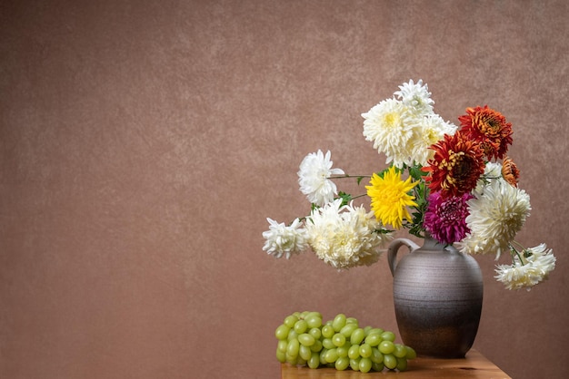A large bouquet of dahlias  bunch of green grapes Orange background White yellow red flowers