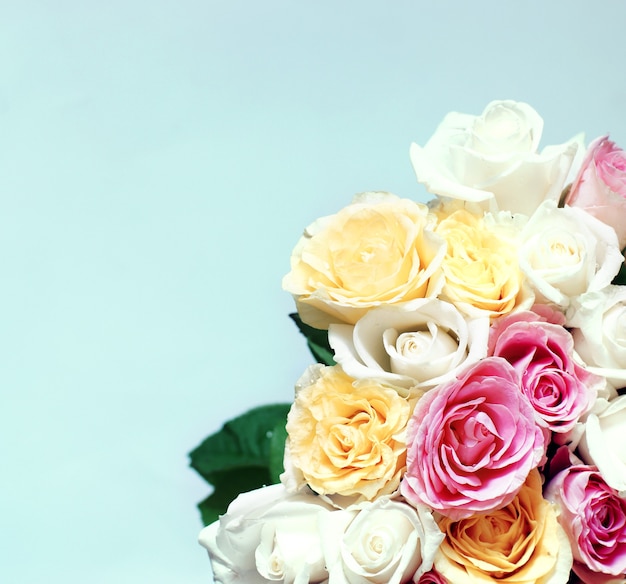 A large bouquet of many beautiful multicolored roses on a light blue background.