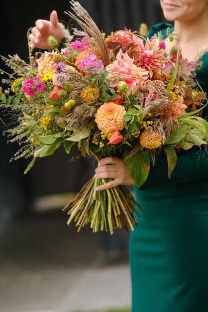 a large bouquet of mixed flowers in the hands of a woman the work of a florist in a flower shop