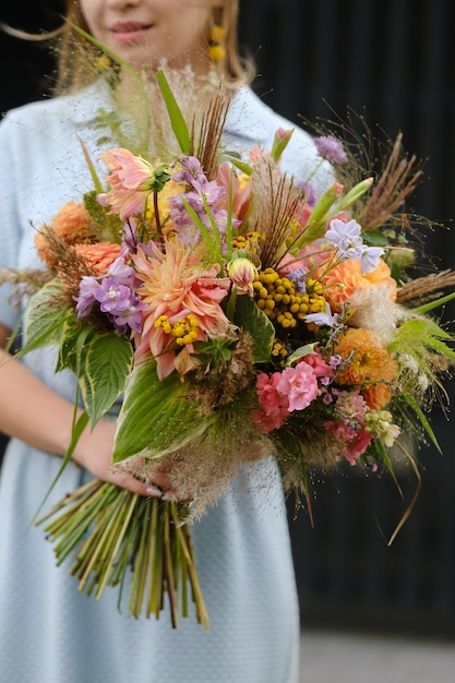 a large bouquet of mixed flowers in the hands of a woman the work of a florist in a flower shop