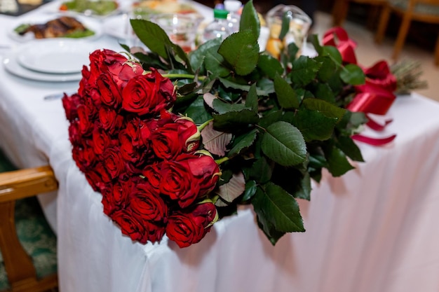 A large bouquet of red roses on a table in a restaurant