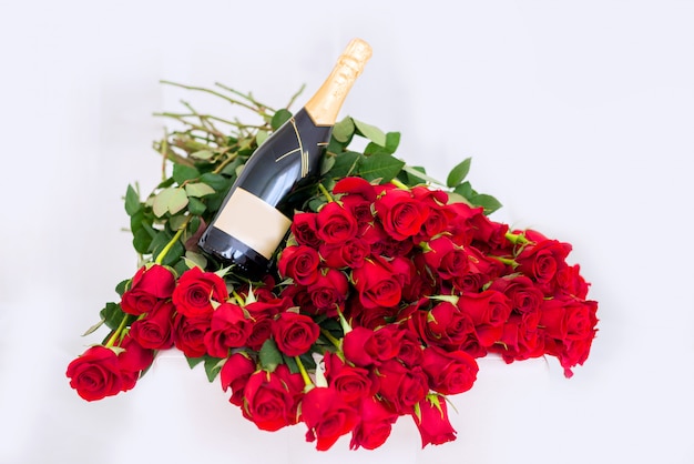 Grande mazzo di rose rosse con una bottiglia di champagne.