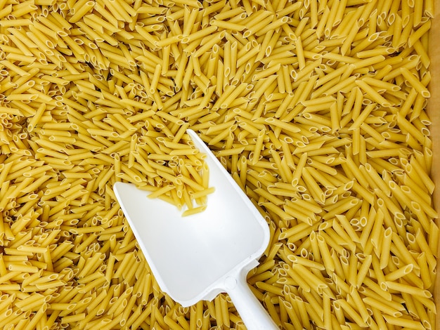 Large box of Italian pasta with a white scoop close-up. Food.