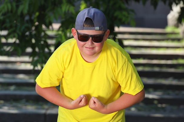 Photo a large boy in a yellow t-shirt tenses his muscle. the concept of body positivity. high quality photo