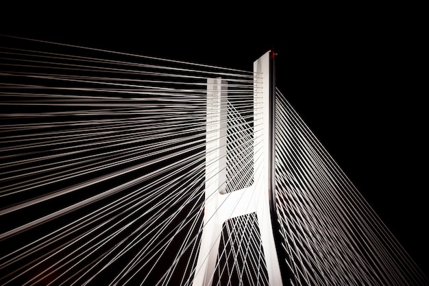 A large bridge with steel cables glows brightly at night