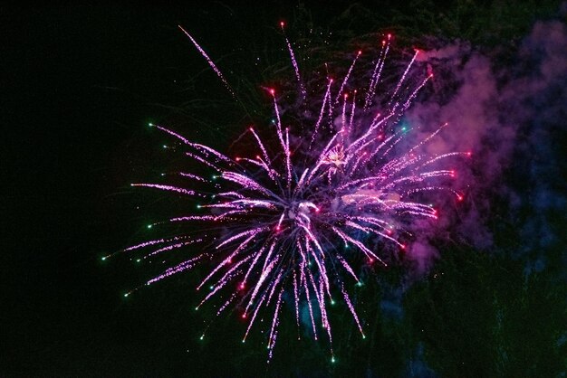 Large and bright festive salute of pink color with haze in the\
night sky