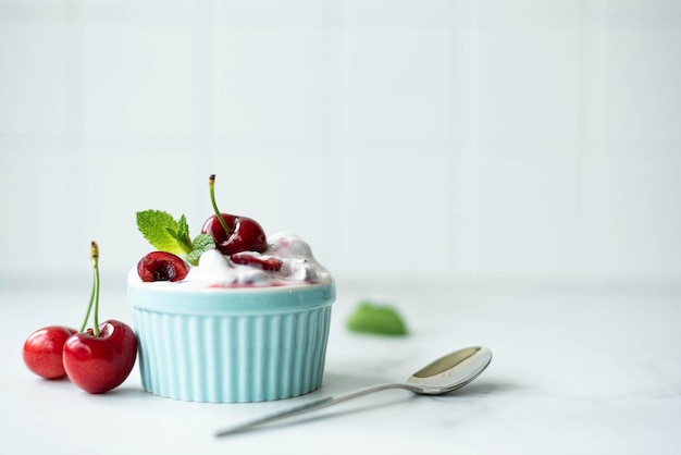 Grandi ciliegie con yogurt greco fatto in casa e menta in una ciotola blu copia spazio