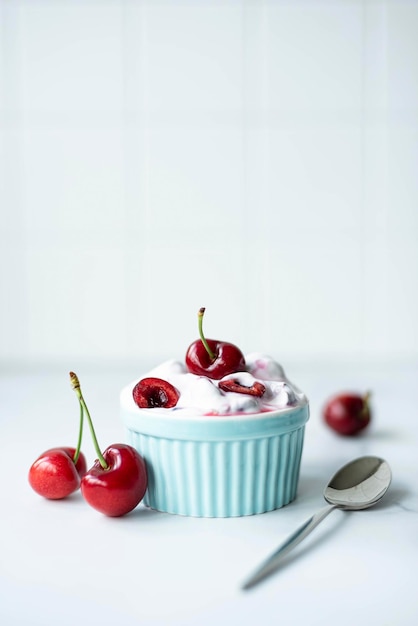 Foto ciliegie grandi con yogurt greco fatto in casa e menta in una ciotola blu