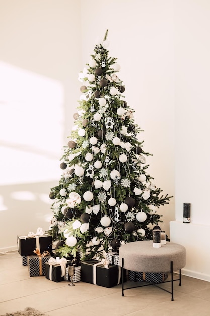 Large christmas tree with decor in the living room against a white wall