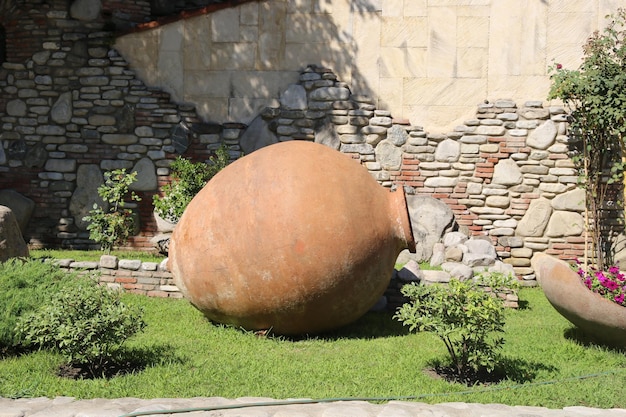 A large clay pot sits in front of a stone wall.