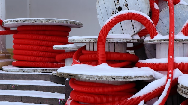 Large coils of red flexible corrugated pipe used to protect cables in electrical installations. Lots of colored polyethylene plastic hose used in construction for plumbing systems.