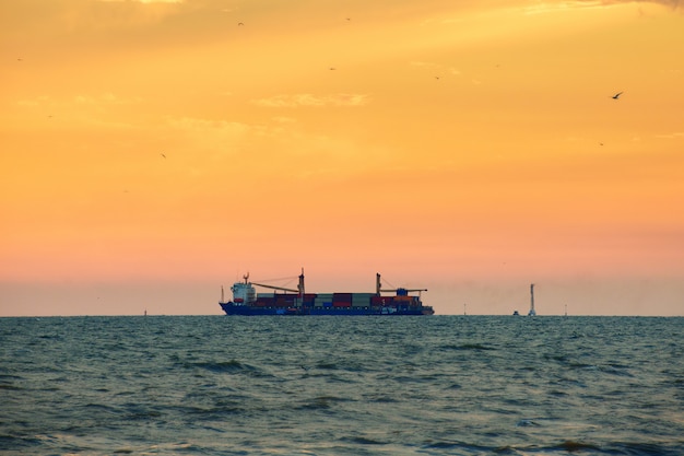 Photo large container ship at sea with sunset sky