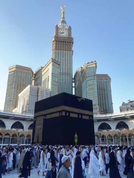 a large crowd of people are walking around a mosque with a clock on the top