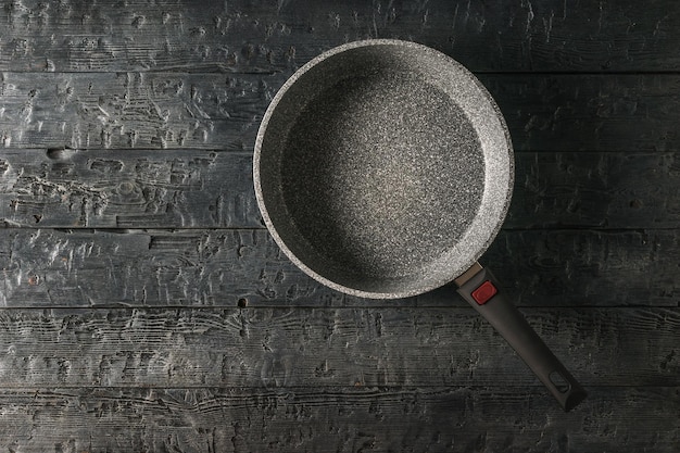 A large deep frying pan on a black wooden table The view from the top