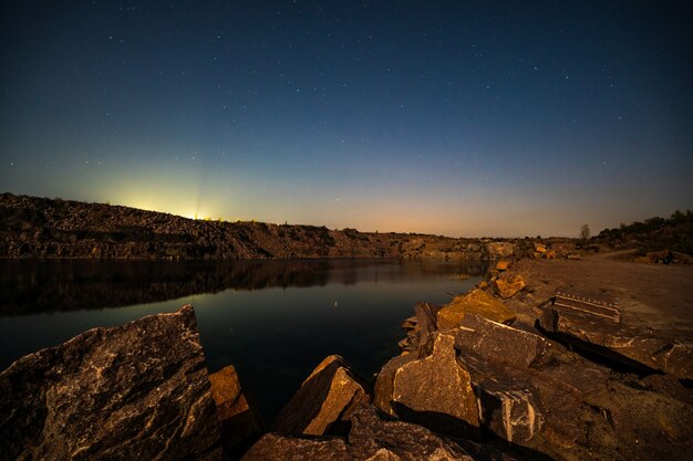 Large deposits of stone materials near a mining mine in the Carpathians against the backdrop of a beautiful night sky with a bright moon