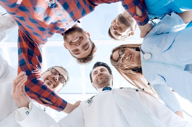 A large diverse medical team standing in a circle everyone is looking down at the camera and smiling isolated on white with a central copyspace