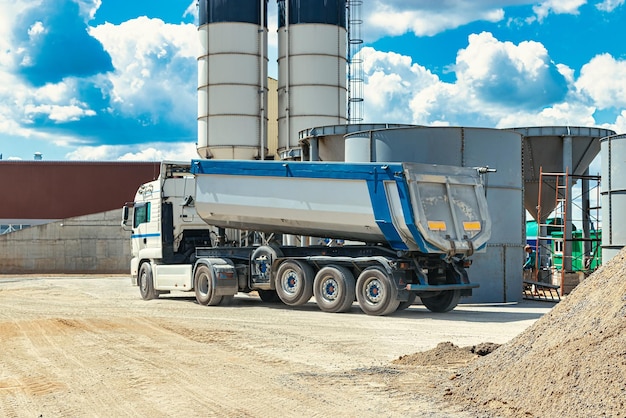 Large dump truck near the concrete factory Car tonar for transportation of heavy bulk cargo Provision of crushed stone and gravel for concrete production